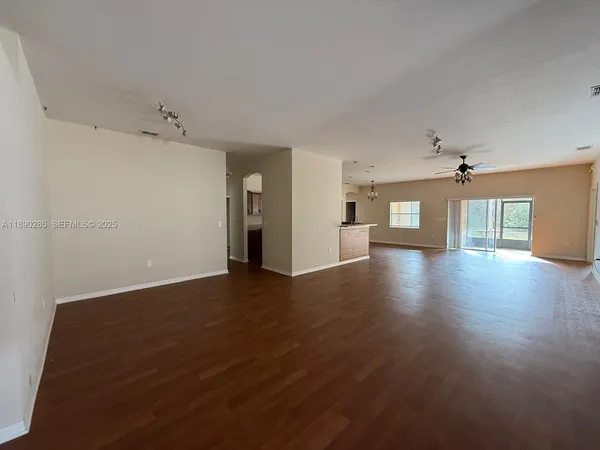 an empty room with wooden floor ceiling fan and windows