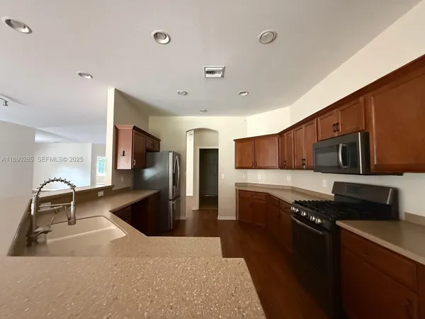 a kitchen with stainless steel appliances granite countertop a sink a stove and a refrigerator