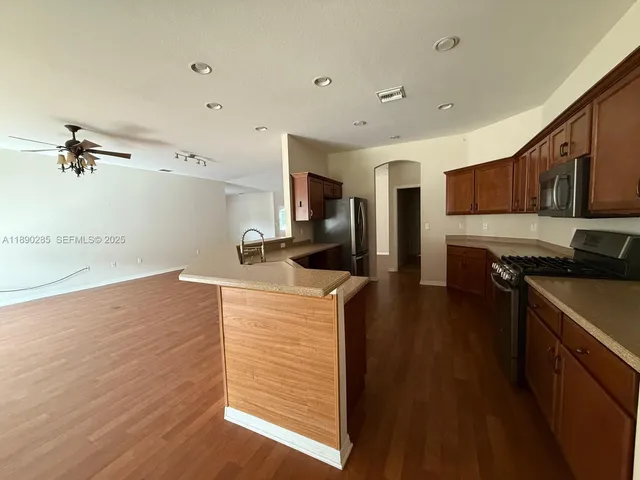 a kitchen with stainless steel appliances granite countertop a refrigerator a stove top oven a sink dishwasher and wooden floor