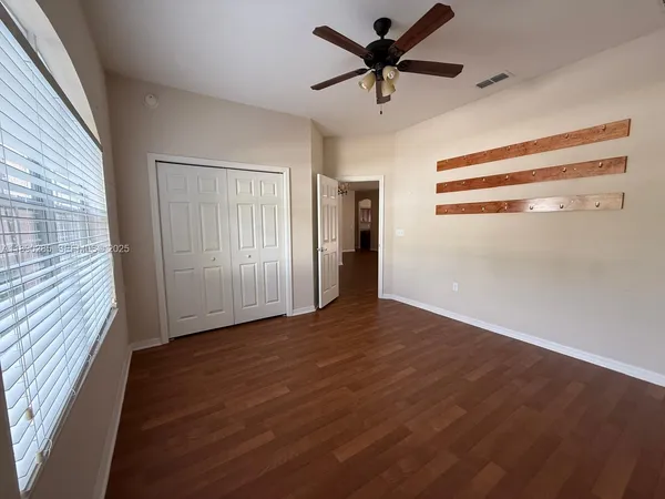 a view of empty room with wooden floor and fan