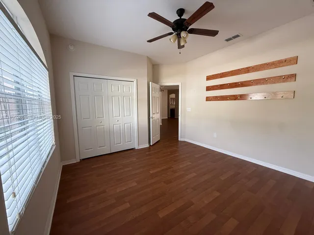 a view of empty room with wooden floor and fan