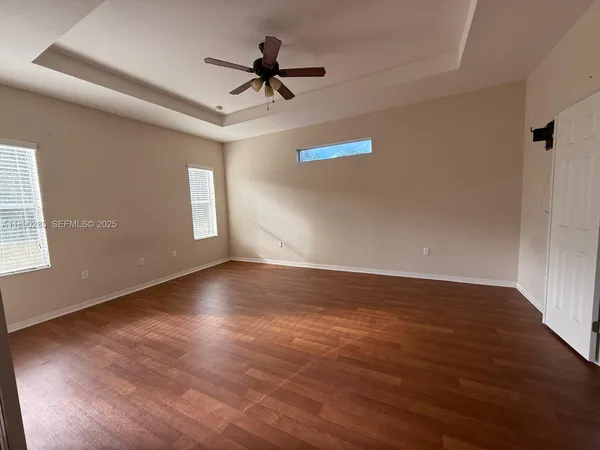 a view of empty room with wooden floor and fan