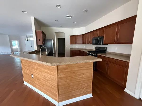 a kitchen with stainless steel appliances kitchen island granite countertop a stove a sink and a refrigerator