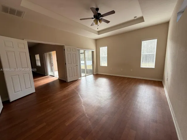a view of an empty room with window and wooden floor