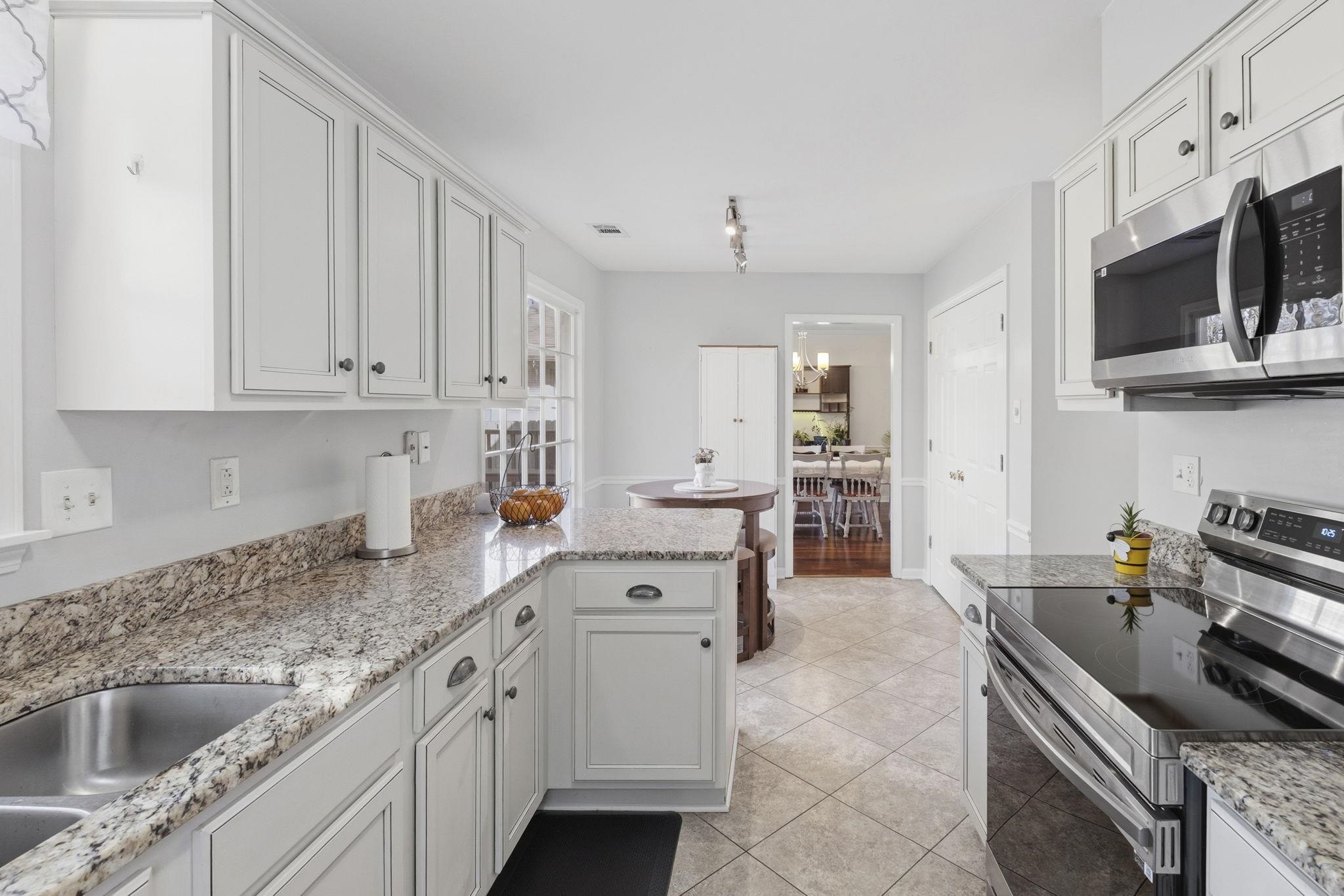 395 Alexander Street Memphis, TN 38111 - Photo 15 of 36 a kitchen with stainless steel appliances granite countertop a sink stove oven and white cabinets