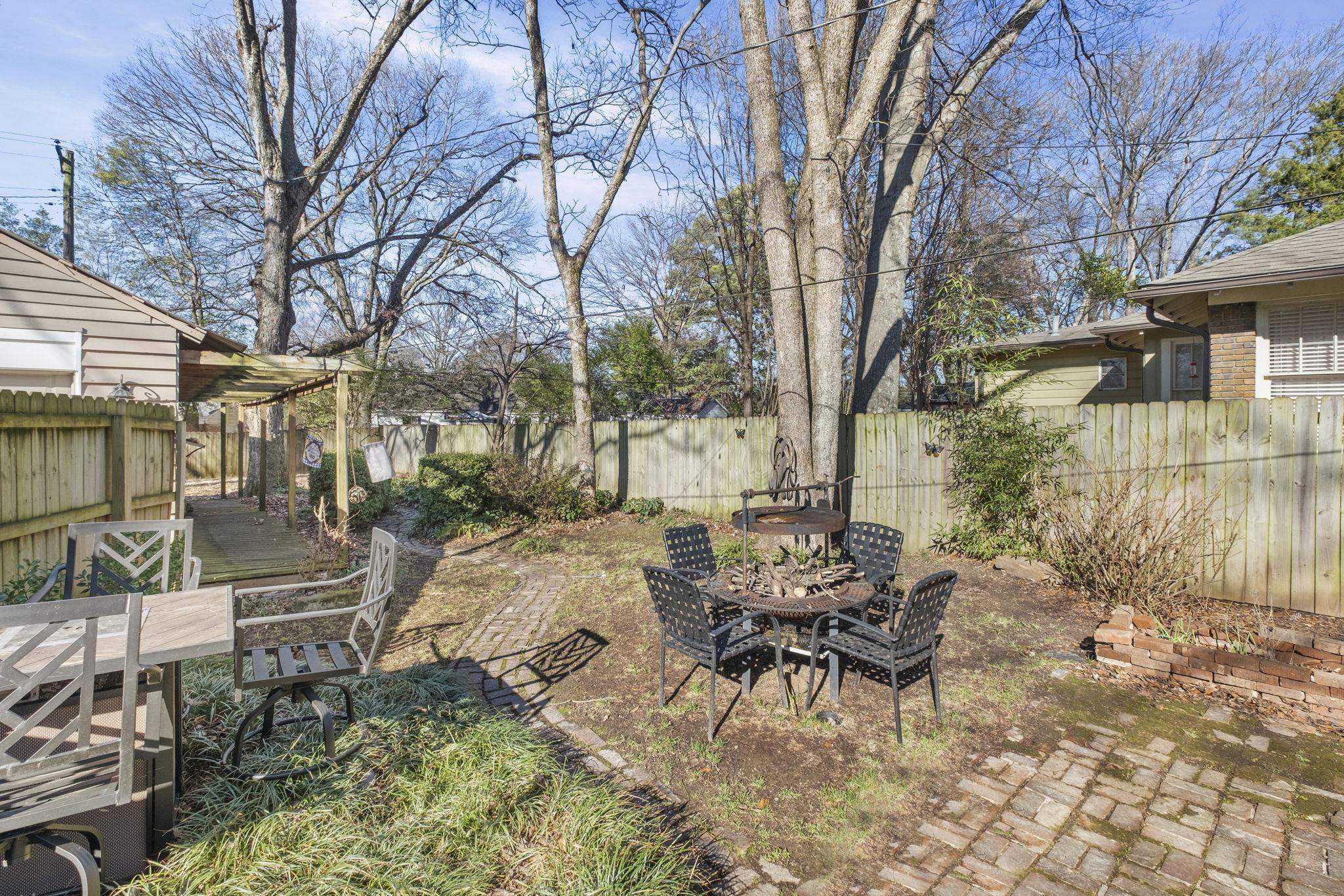 395 Alexander Street Memphis, TN 38111 - Photo 27 of 36 a view of a patio with table and chairs with wooden fence and large trees