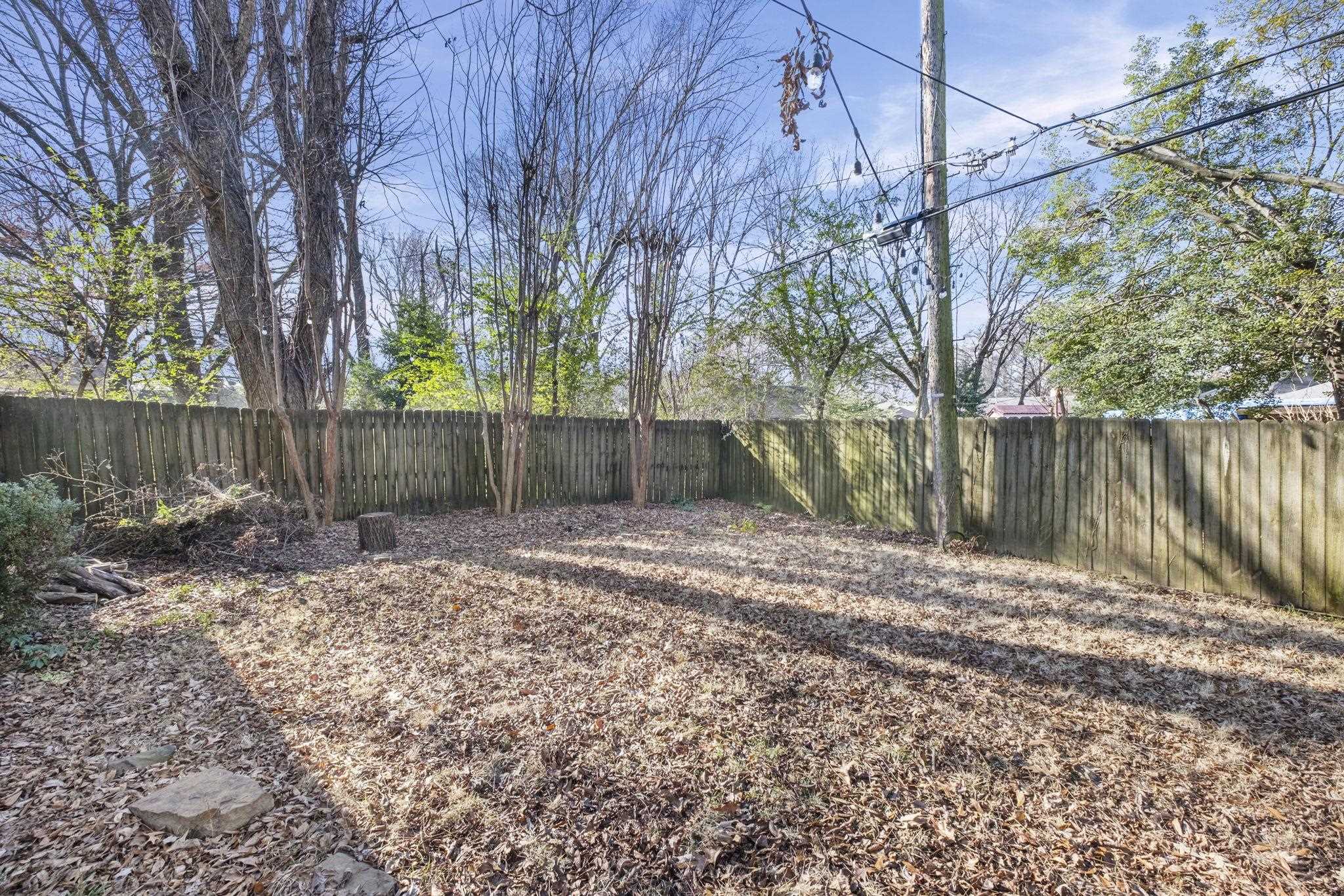 395 Alexander Street Memphis, TN 38111 - Photo 30 of 36 a backyard of a house with large trees and wooden fence