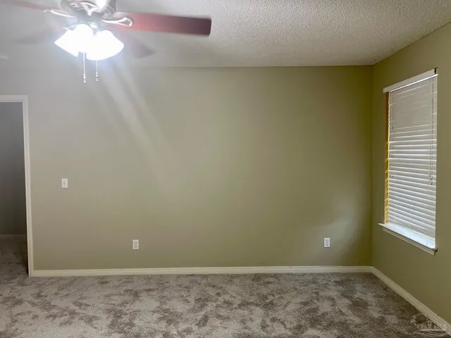 an empty room with windows and chandelier fan