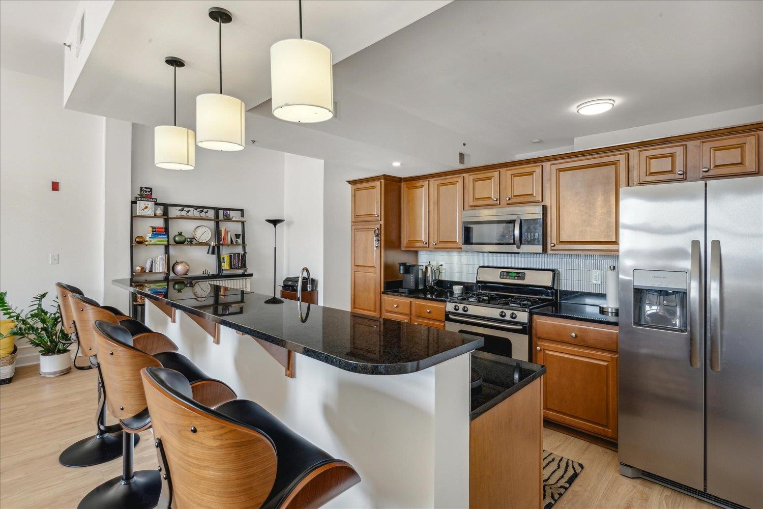 648 Riverside Drive, Unit 411 Memphis, TN 38103 - Photo 10 of 32 Kitchen with a center island, backsplash, light hardwood / wood-style flooring, appliances with stainless steel finishes, and a breakfast bar area
