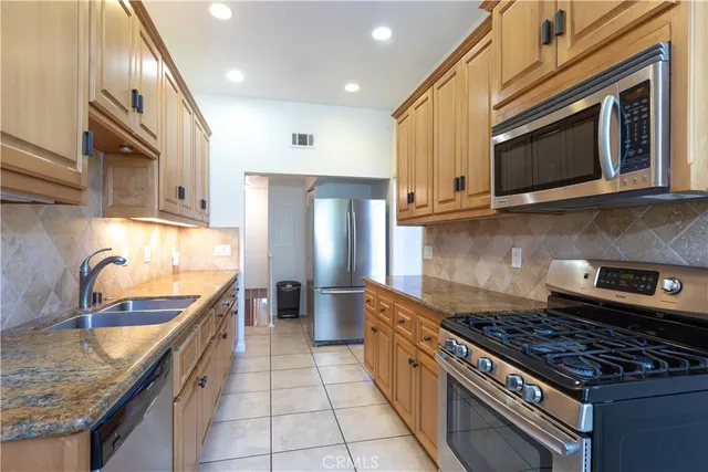 a kitchen with stainless steel appliances granite countertop a stove a sink and a microwave