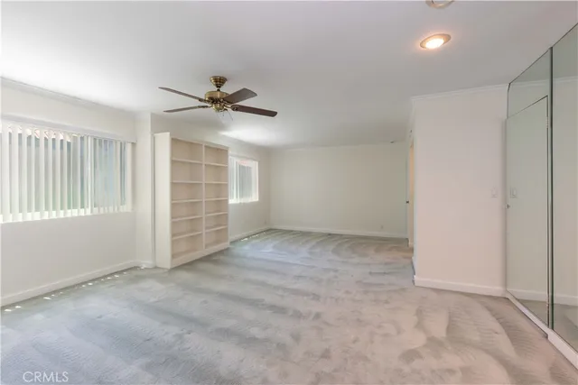 an empty room with closet and a ceiling fan
