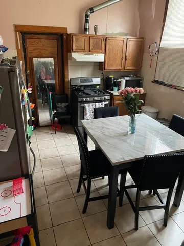 a kitchen with stainless steel appliances a stove a refrigerator a sink a dining table and chairs