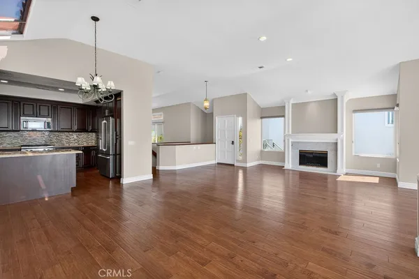 a view of an empty room with wooden floor fireplace and a window