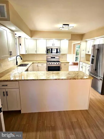 a large kitchen with granite countertop a sink and a stove top oven with wooden floor