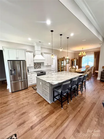a kitchen with stainless steel appliances kitchen island granite countertop a table chairs and a refrigerator