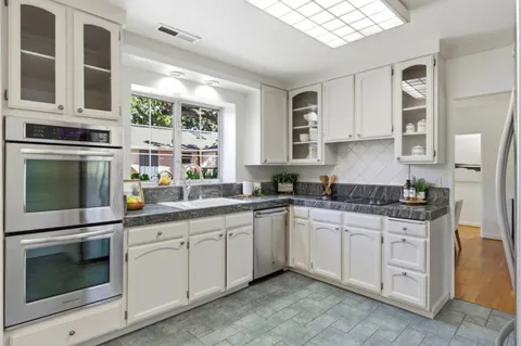 a kitchen with stainless steel appliances granite countertop a kitchen island a stove a table and chairs