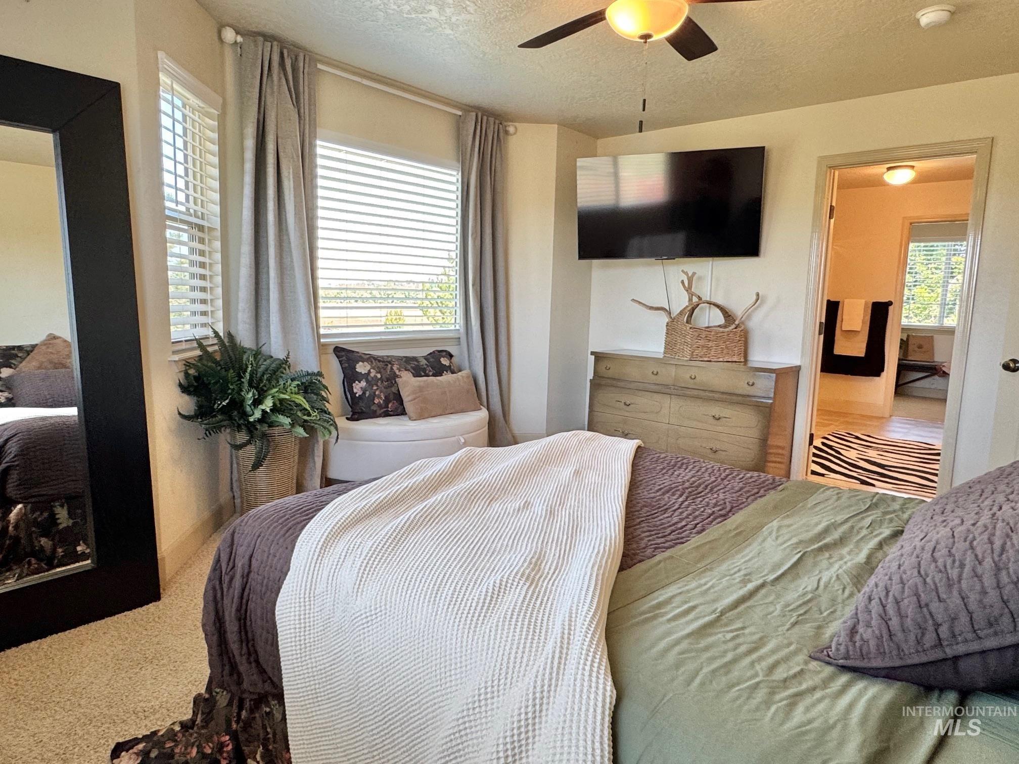 9299 Kemp Road Middleton, ID 83644 - Photo 23 of 50 Carpeted room featuring a ceiling fan with integrated lighting, multiple windows with blinds, and a doorway leading to an adjoining space
