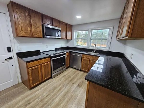 a kitchen with granite countertop wooden cabinets stainless steel appliances a window and a sink