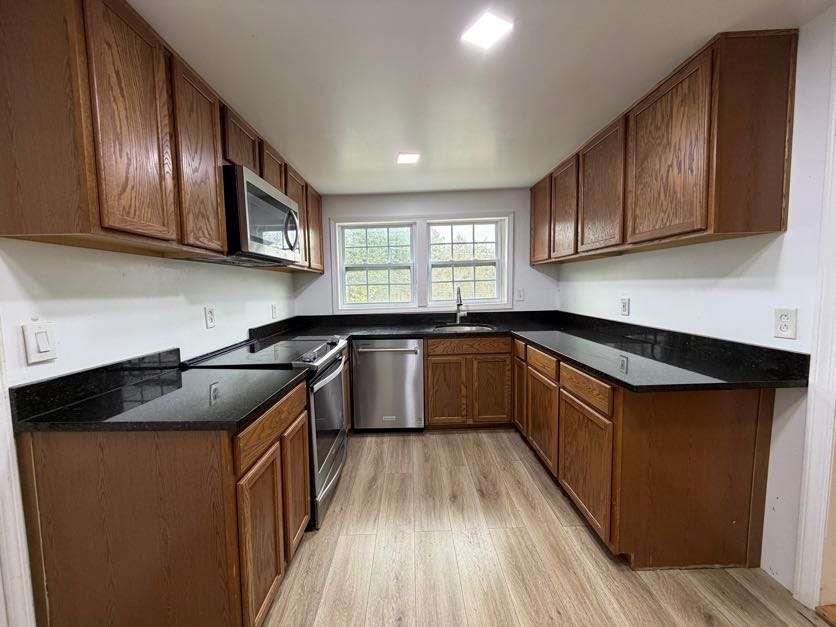 1252 Lawrenceville-Suwanee Road Lawrenceville, GA 30043 - Photo 32 of 64 a kitchen with granite countertop stainless steel appliances a sink dishwasher a stove top oven a refrigerator with wooden cabinets and floor