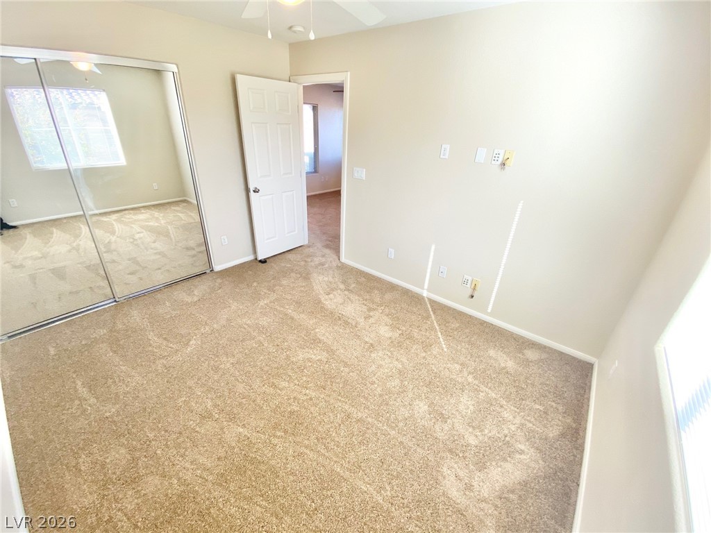 8569 Rhamus Court Las Vegas, NV 89149 - Photo 19 of 35 A quiet bedroom featuring plush carpet flooring and a mirrored closet, ready for personalization.