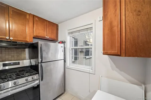 a kitchen with stainless steel appliances granite countertop a refrigerator a stove and a sink with wooden cabinets