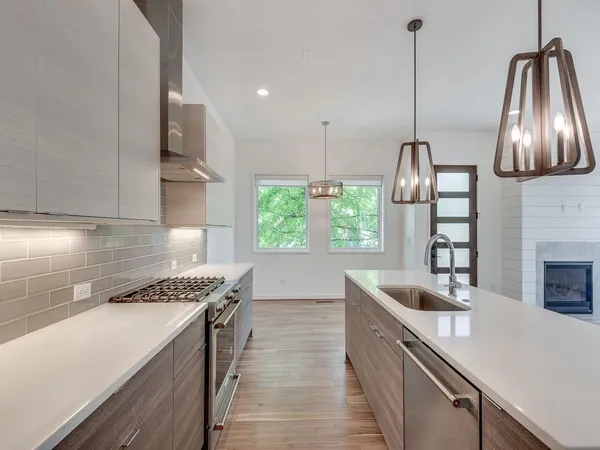a kitchen with stainless steel appliances granite countertop a sink a stove and a wooden floors