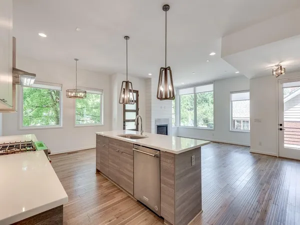 a large kitchen with kitchen island a stove a sink a center island wooden floor and windows
