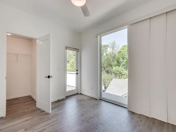 a view of an empty room with wooden floor and a window