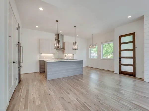 a room with kitchen island stainless steel appliances wooden floor and window