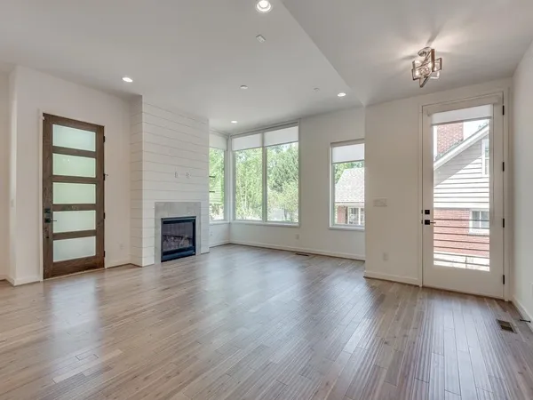 an empty room with windows fireplace and wooden floor