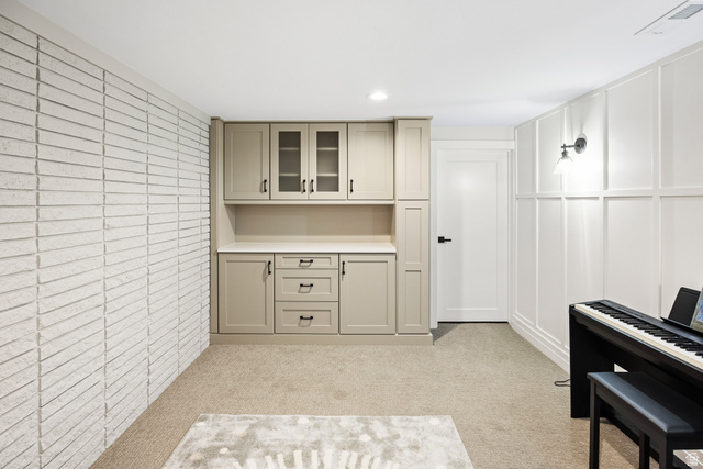 1774 Country Club Drive Logan, UT 84321 - Photo 16 of 28 Built-in cabinetry with glass-front uppers and a light countertop, complemented by a textured brick-style wall and panel molding