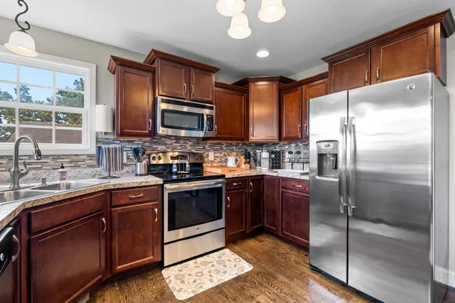 a kitchen with stainless steel appliances granite countertop a refrigerator a stove a sink and a microwave