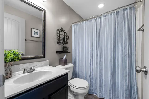 a bathroom with a granite countertop sink and a toilet