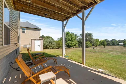 a view of a patio with lawn chairs floor to ceiling window and yard