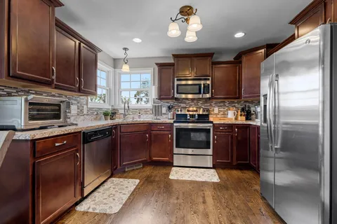 a kitchen with stainless steel appliances granite countertop a refrigerator a stove top oven a sink and dishwasher