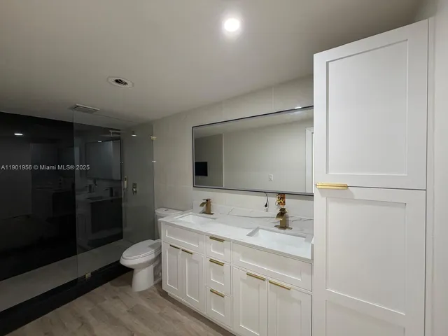 a bathroom with a toilet sink double vanity and mirror