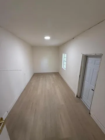 an empty room with wooden floor and window