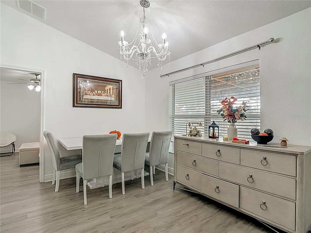 13108 Oneida Street Spring Hill, FL 34609 - Photo 13 of 62 a dining room with chandelier and wooden floor