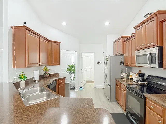 a kitchen with stainless steel appliances granite countertop a sink dishwasher stove and oven with wooden cabinets