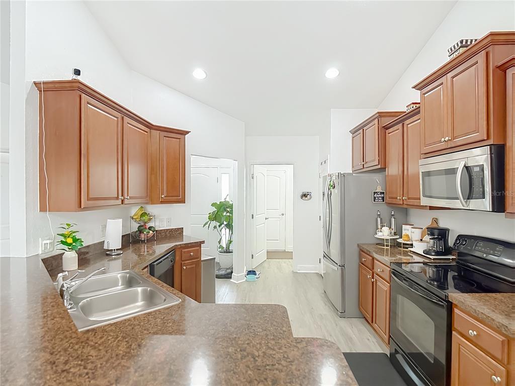 13108 Oneida Street Spring Hill, FL 34609 - Photo 17 of 62 a large kitchen with stainless steel appliances granite countertop a refrigerator a stove a sink a counter space and cabinets