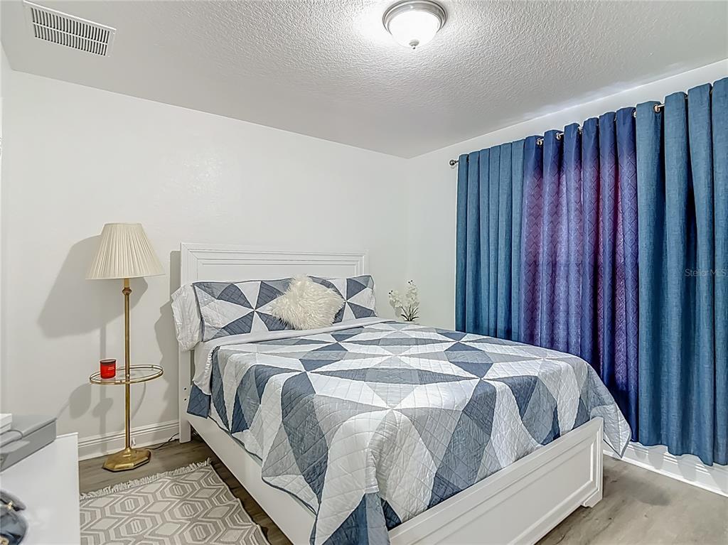 13108 Oneida Street Spring Hill, FL 34609 - Photo 35 of 62 a bed sitting in a bedroom next to a window and a chandelier