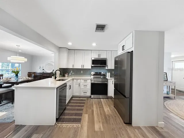 a kitchen with a refrigerator a sink dishwasher and a stove with wooden floor