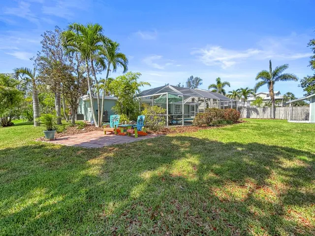 a view of a house with a big yard and palm trees