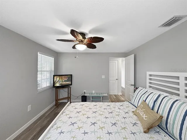 a bedroom with a bed and a dresser with wooden floor