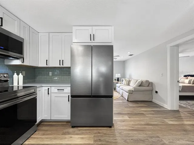 a kitchen with stainless steel appliances granite countertop a refrigerator a stove top oven a sink dishwasher and a refrigerator with wooden floor