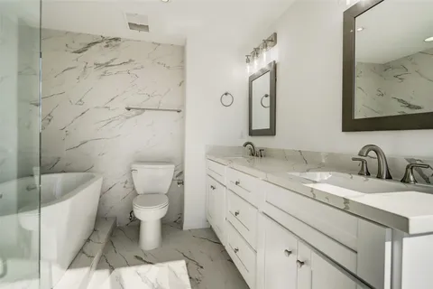 a bathroom with a granite countertop sink mirror vanity and toilet