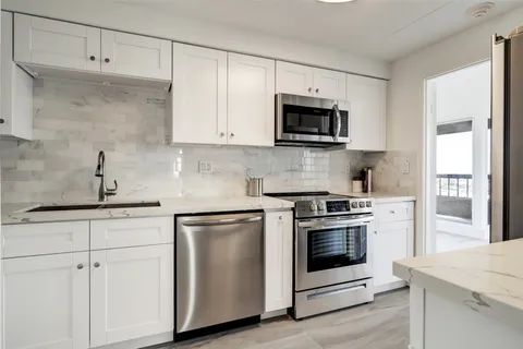 a kitchen with white cabinets and stainless steel appliances