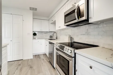a kitchen with granite countertop white cabinets stainless steel appliances and sink
