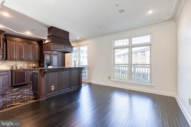 a kitchen with kitchen island granite countertop a stove top oven a sink and a wooden floors