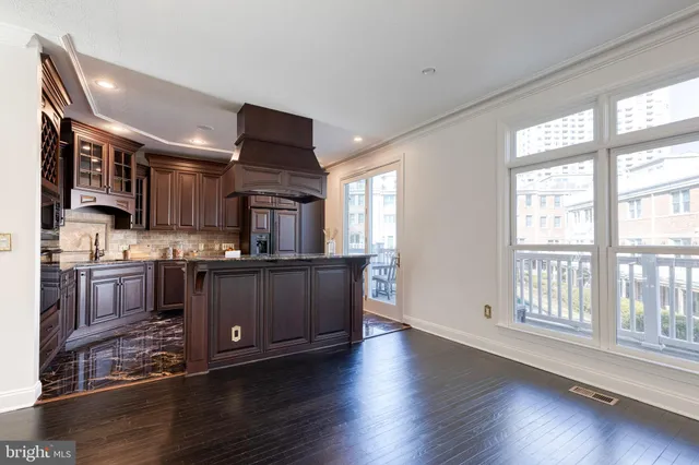 a kitchen with stainless steel appliances kitchen island granite countertop a refrigerator a sink a stove and oven with wooden floor